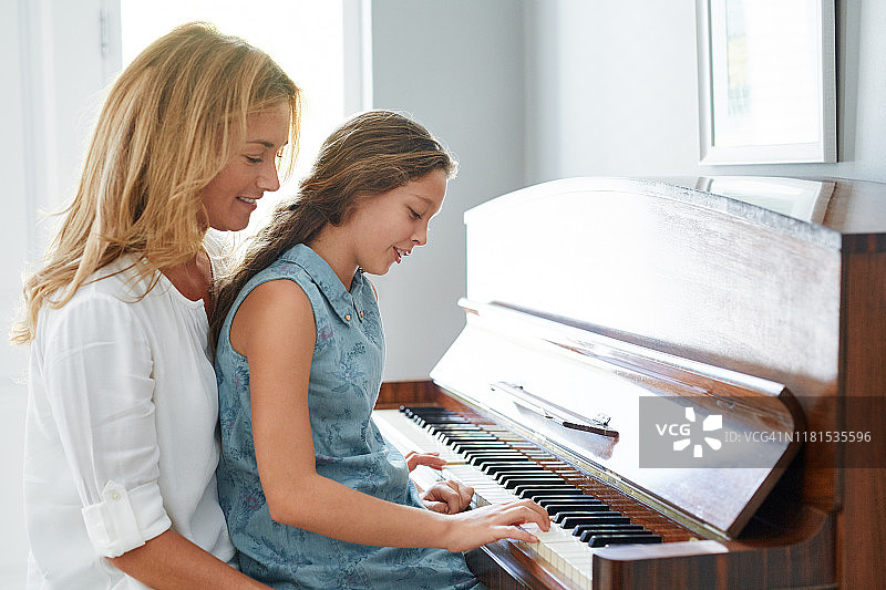 微笑的母亲和女儿在家弹钢琴图片素材