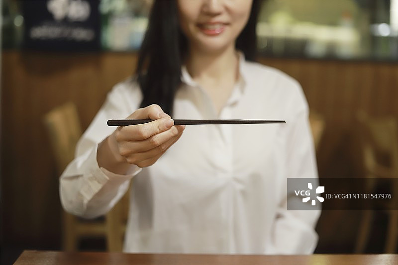 女人在餐厅里拿着筷子图片素材