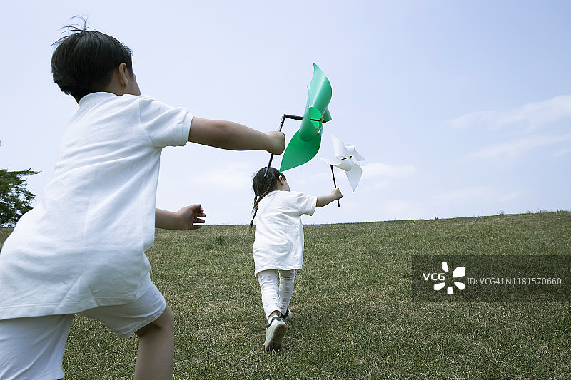 孩子们在田野里玩风车玩具的背影图片素材