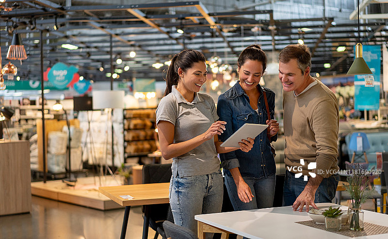 快乐的售货员向在中老年夫妇展示平板电脑上的设计，他们正在家居店寻找家具图片素材