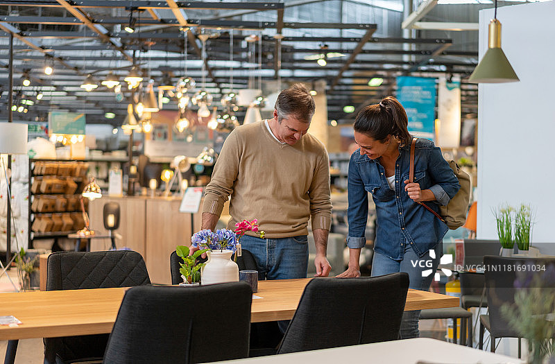 快乐的中年夫妇在家具店挑选餐桌图片素材