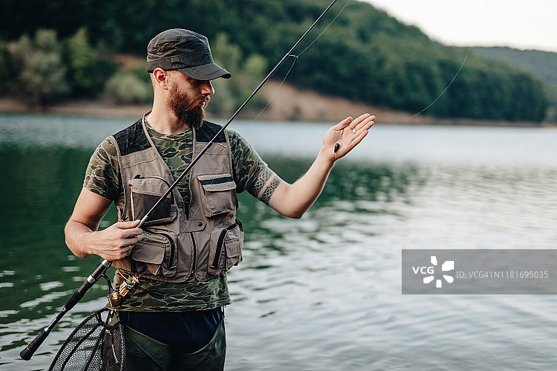 渔民站在河边手持钓竿图片素材