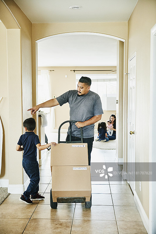 儿子帮助父亲将箱子搬进新家图片素材