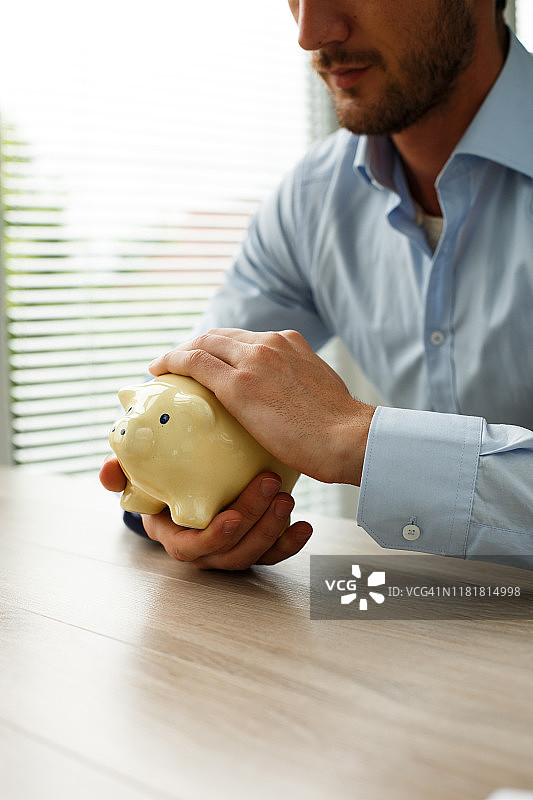 年轻男人抱着一个储蓄罐图片素材