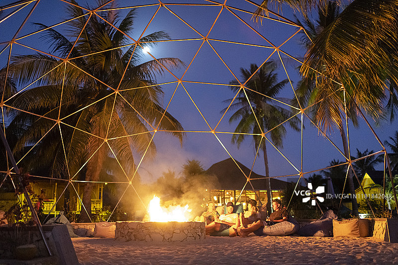 朋友们在豪华海滩度假村的篝火旁享受时光图片素材