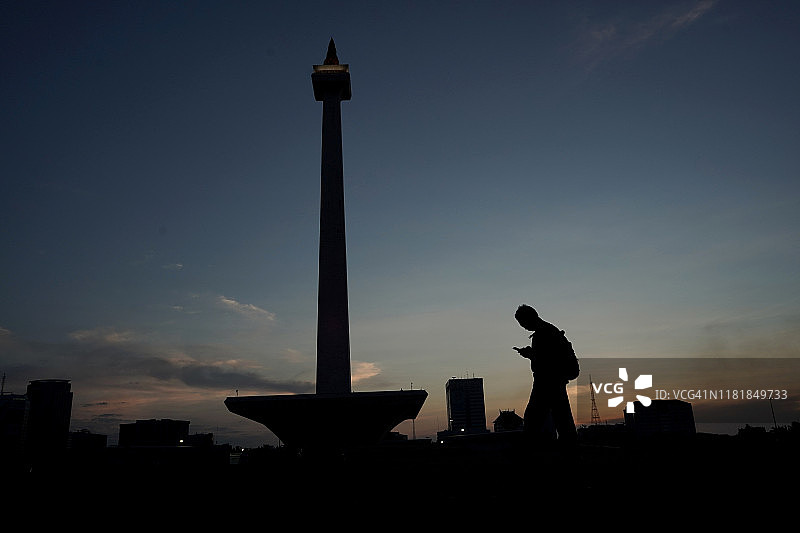 男人在雅加达纪念碑旁使用手机图片素材