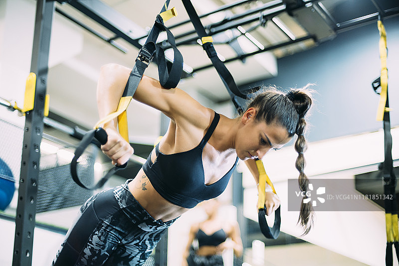 年轻女人在健身房做悬挂训练图片素材