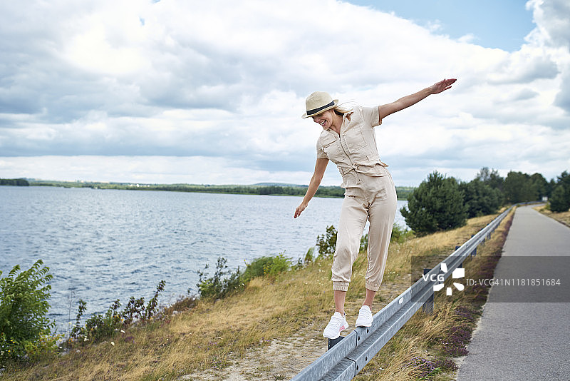 在湖边撞击护栏上保持平衡的快乐女人图片素材