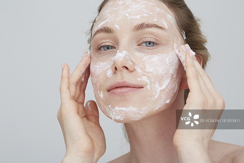 金发年轻女子涂抹面霜的肖像图片素材
