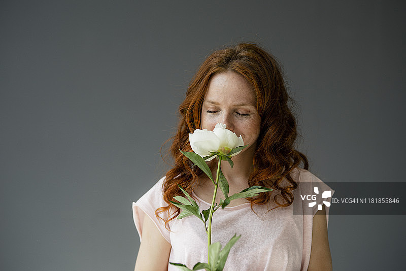 红发女人闻白牡丹肖像图片素材