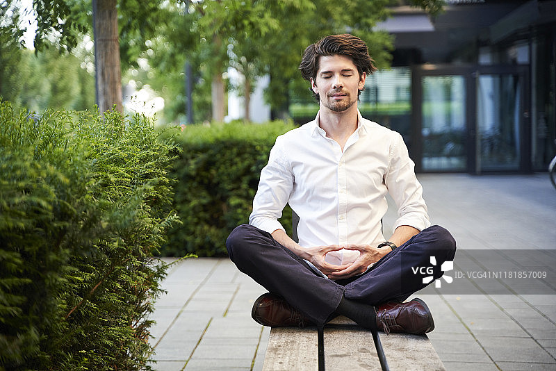 在城市长椅上做瑜伽的商人图片素材