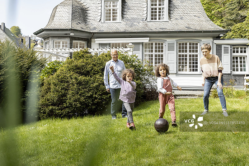 幸福的大家庭在花园里踢足球图片素材