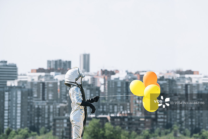 男孩打扮成宇航员在城市里拿着气球图片素材
