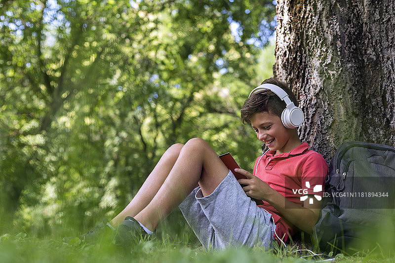 男孩在户外使用手机和耳机放松图片素材