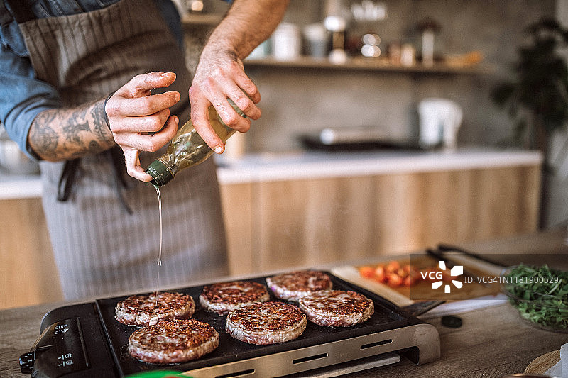身份不明的男人在电烤炉上添加食用油图片素材