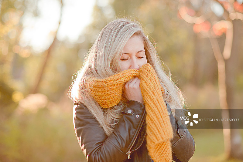 秋日公园里围着舒适橙色围巾的美丽女人图片素材