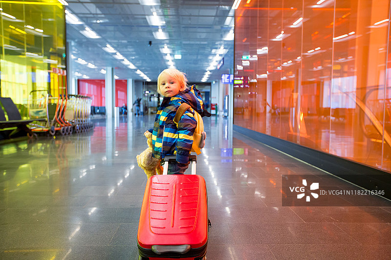 可爱的男婴在机场候机大厅等待登机，享受积极的家庭旅行图片素材