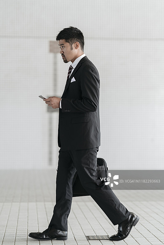 在城市里用手机走路的年轻商人图片素材