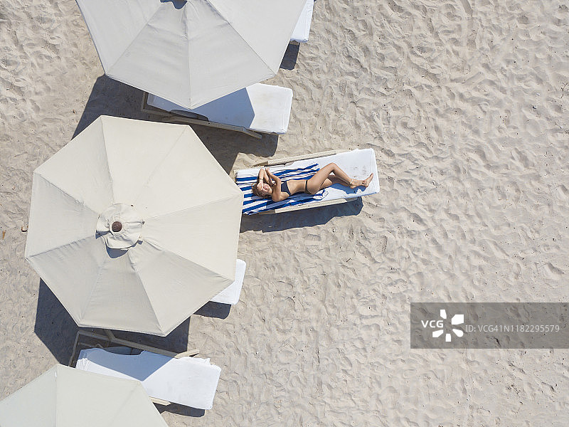 躺在印度尼西亚吉利群岛吉利艾尔海滩日光浴躺椅上的女人图片素材