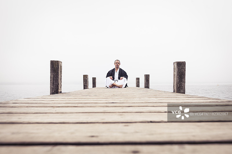 男人坐在施塔恩贝格湖的码头上做瑜伽图片素材