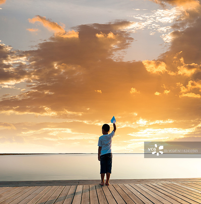 小男孩在湖边拿着纸飞机图片素材