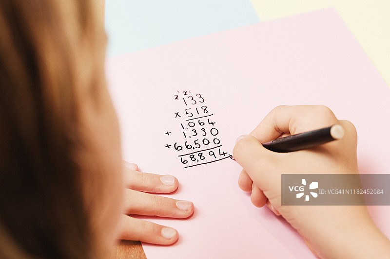 12岁女孩在做数学家庭作业：长乘法图片素材
