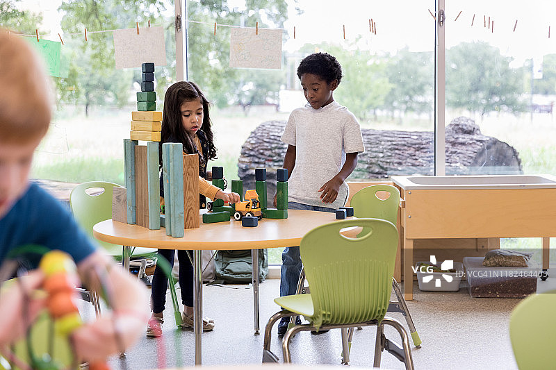 两个学龄前的朋友在桌子上玩汽车和积木图片素材