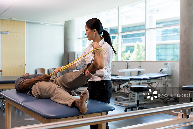 中年治疗师指导中年男人伸展腿部图片素材