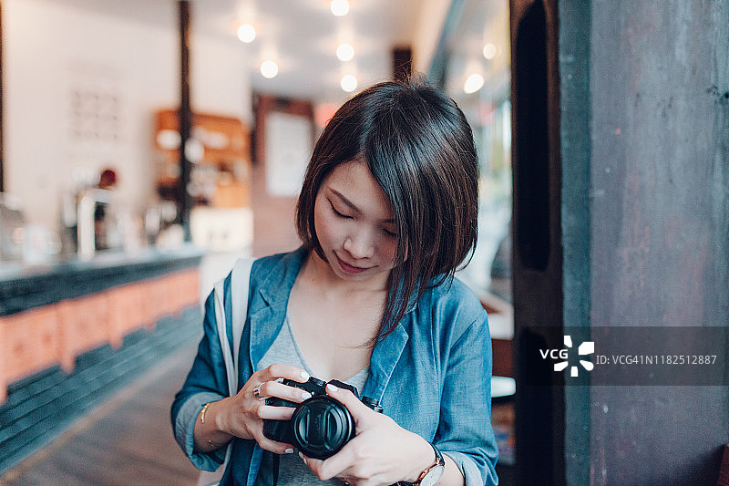在咖啡店休息并手持相机的年轻女人图片素材