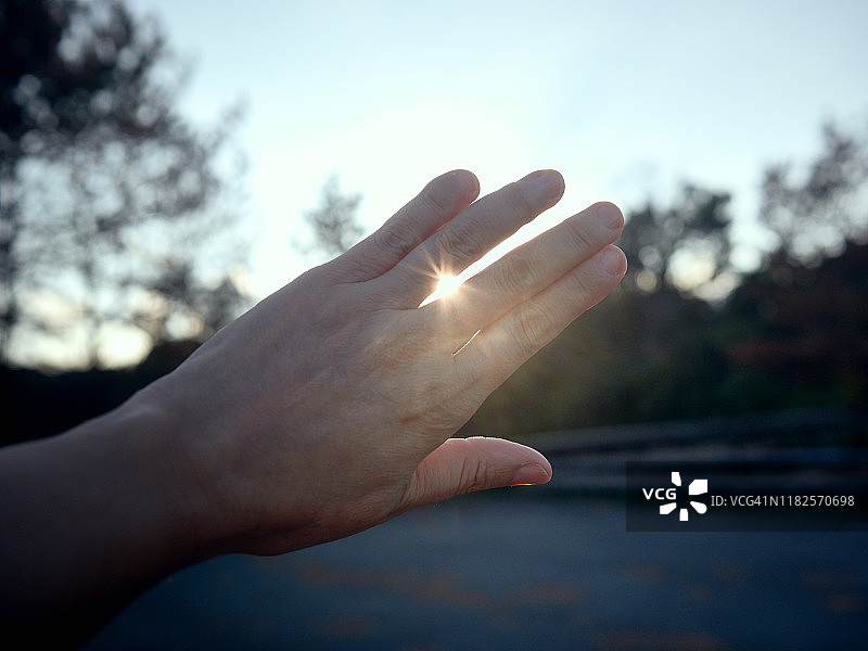 日落时分在海边沐浴阳光的手图片素材