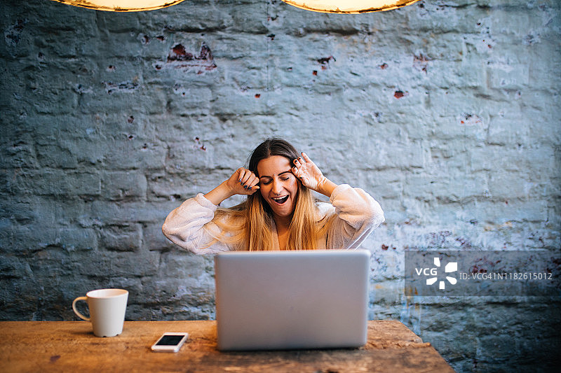 在家用笔记本电脑和咖啡的困倦女人图片素材