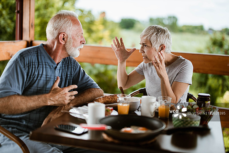 一对愤怒的中年夫妇在露台上吃早餐时争吵图片素材