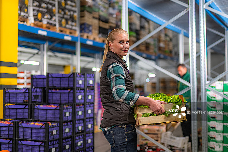 拿着装有新鲜生菜的木箱的女人图片素材
