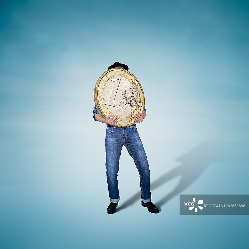 男人拿着大而重的欧元硬币，金融概念图片素材