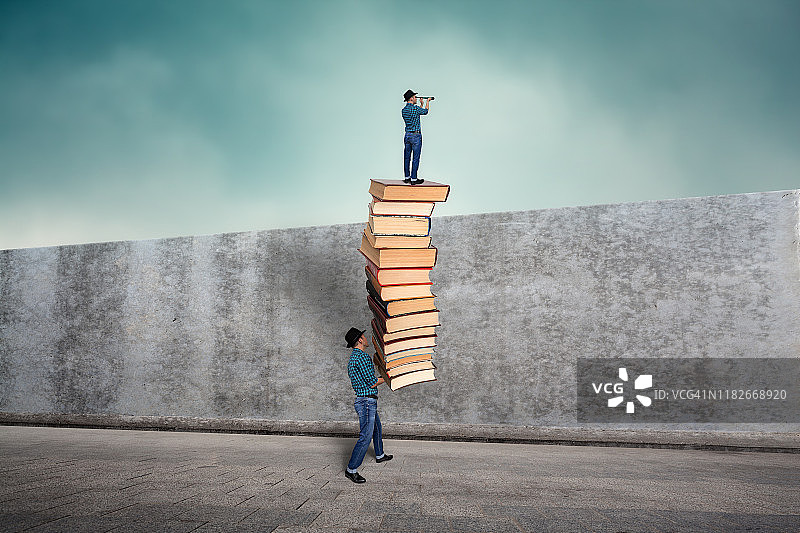 站在书上越过墙壁向外观望的男人图片素材