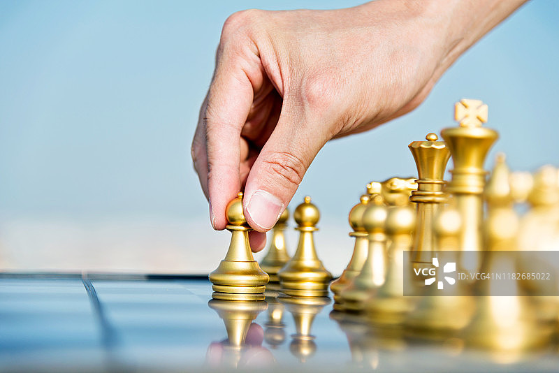 男人手持金色棋子，走出第一步图片素材