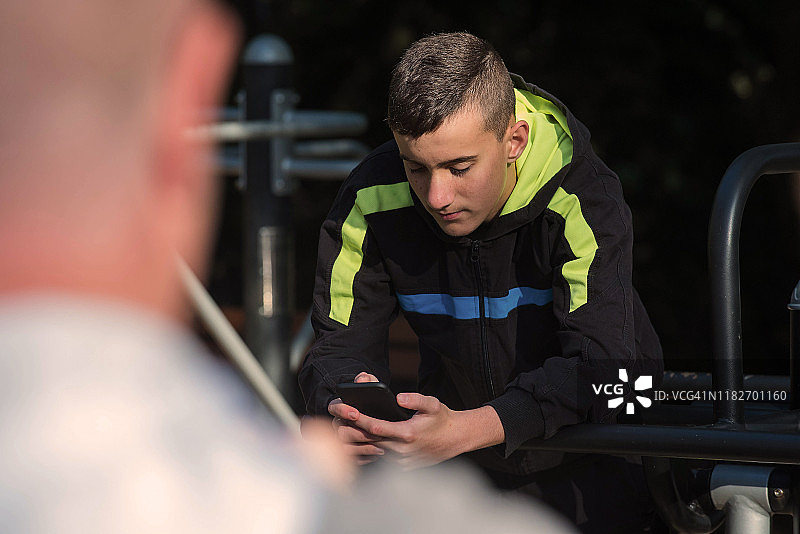 在操场上阅读短信的青少年图片素材