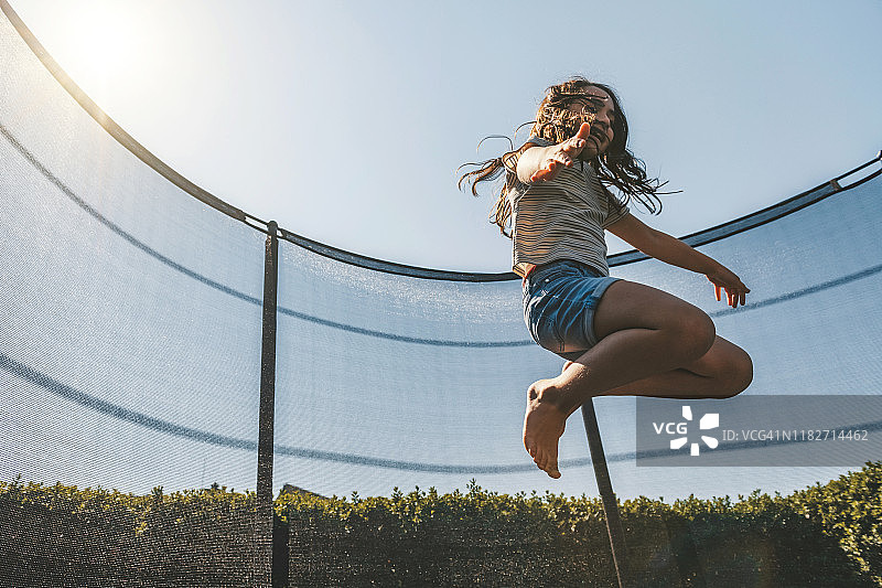在蹦床上跳跃的小女孩图片素材