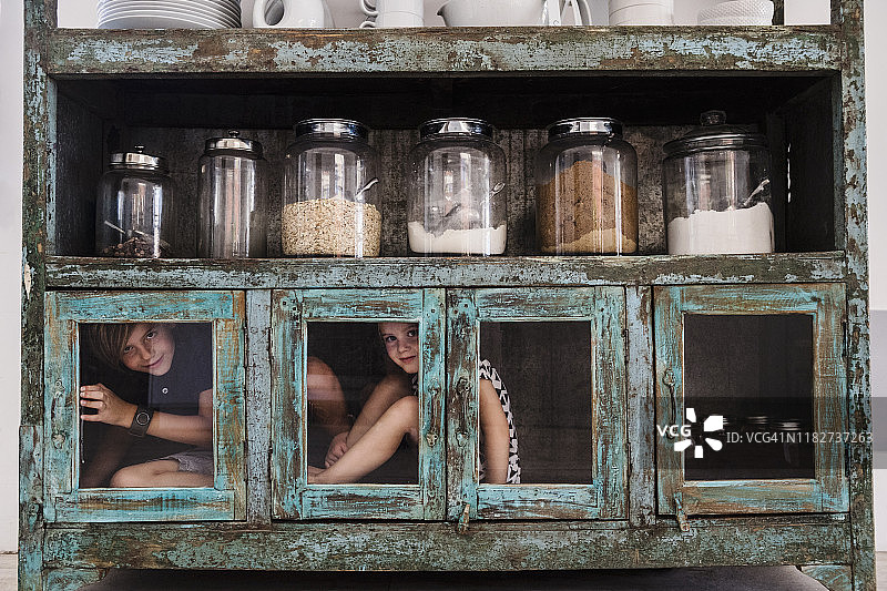 孩子们躲在厨房的橱柜里图片素材