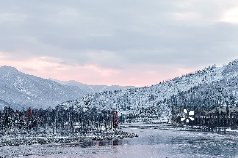 俄罗斯西伯利亚阿尔泰山区，卡тун河上方的冬日日落，雪 покрытые森林图片素材