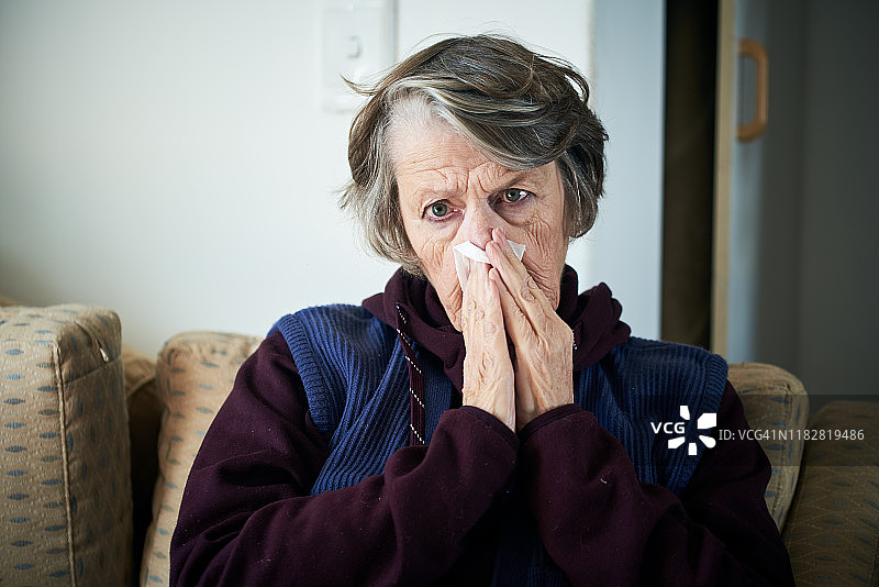 感冒的老年妇女在擤鼻涕图片素材