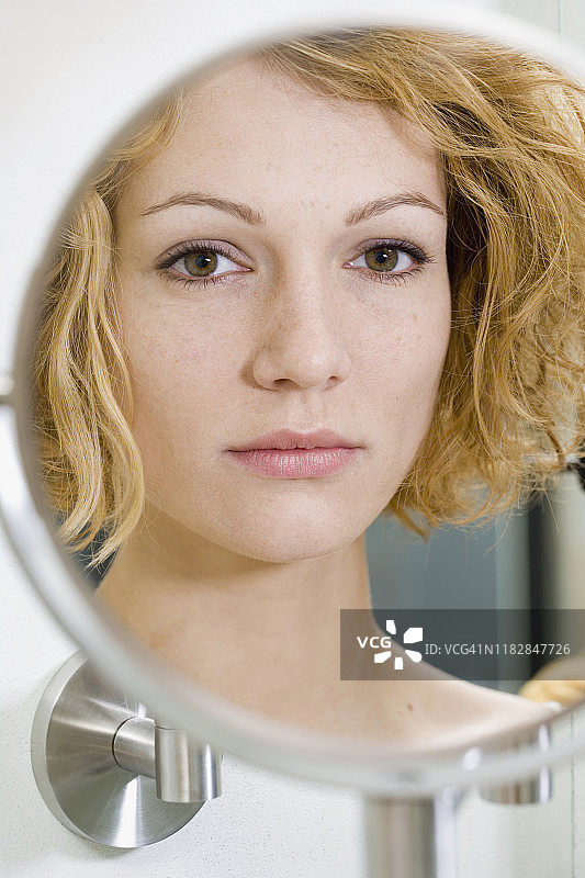 照镜子时面露忧色的女人图片素材