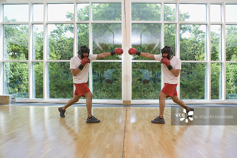 男子对着镜子中的自己进行拳击训练图片素材