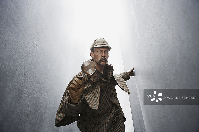 打扮成夏洛克·福尔摩斯的男人拿着放大镜图片素材