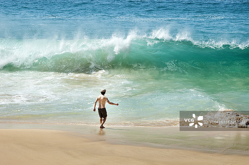 西班牙男人在海滩面对海浪图片素材