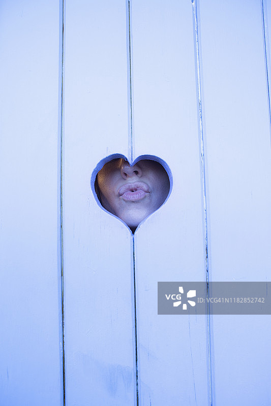 透过心形木头嘟嘴的女人特写图片素材