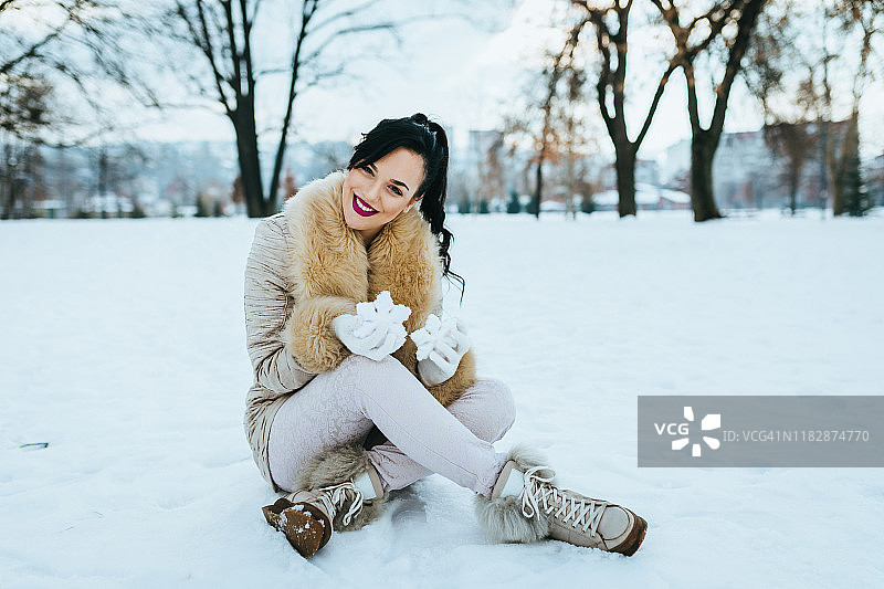 在公园里享受下雪的冬日并拿着雪花的女人图片素材