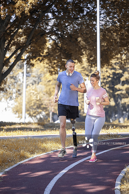 在公园里跑步并与女教练交谈的残疾年轻男人图片素材