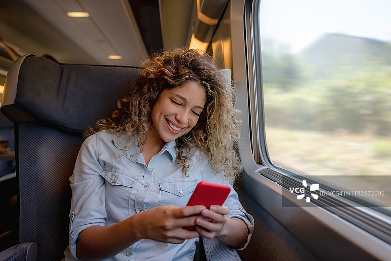 快乐的女人在火车上发短信图片素材