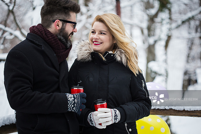 情侣在下雪的公园里喝咖啡图片素材
